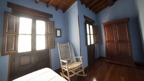 Una habitación con suelo de madera, una mecedora y un armario.