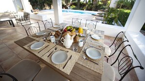A dining table set outdoors with a view of a pool and palm trees. - Villa With Private Pool & Garden, 5 minutes walk to the Beach (Eivissa)