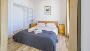 Une chambre à coucher comprenant un lit, des tables de chevet, une armoire et un tableau encadré accroché au mur.