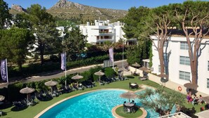 Un complexe hôtelier doté d’une piscine, de chaises longues et offrant une vue sur un paysage montagneux.
