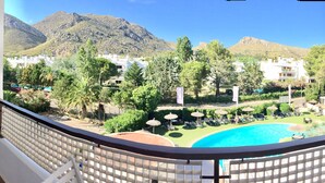 Un balcon offrant une vue sur une piscine, des chaises longues et un paysage montagneux.