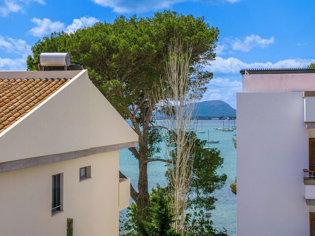 Ein Küstengebäude mit Ziegeldach, einem Baum davor und Blick auf Boote auf dem Wasser.