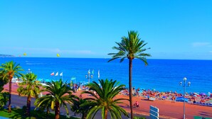 Een strand met palmbomen, parasols en mensen.