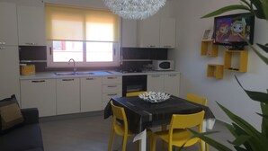 A modern kitchen with white cabinets, a black countertop, and a yellow chair at the dining table. - Casa Anna 800 meters from the SEA .... (Balestrate)