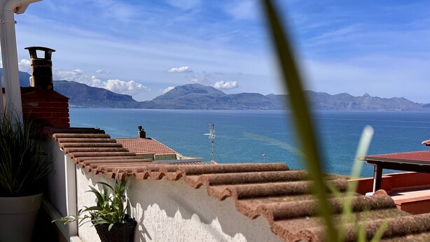 A balcony with terracotta tiles, a potted plant, and a view of the sea and mountains. - Casa Anna 800 meters from the SEA .... (Balestrate)