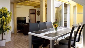 Uma sala de estar moderna com área de jantar, vigas de madeira, televisão e uma janela grande.