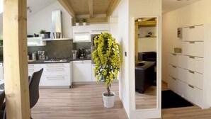 Uma cozinha moderna com armários brancos, uma ilha central e um vaso com planta.