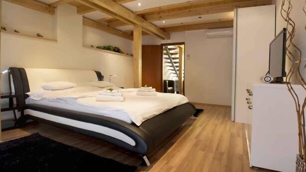 Quarto moderno com cama, mesa de cabeceira e guarda-roupa branco.