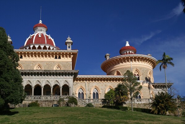 Un edificio grande e histórico con dos torres abovedadas, ventanas de arco y fachada de piedra.