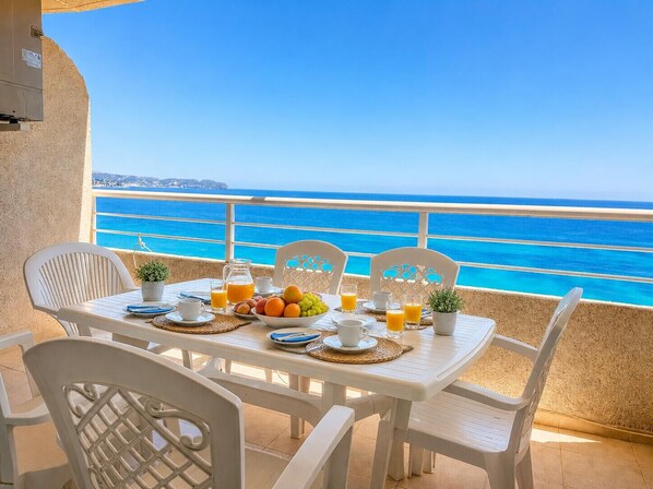 A table set with breakfast items and a view of the sea.