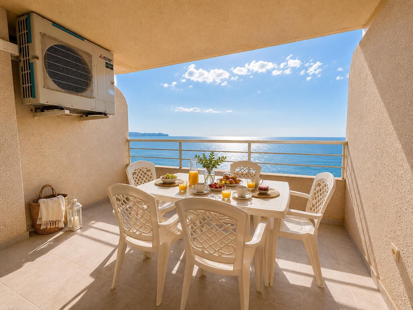 A balcony with a table set for breakfast, overlooking a clear blue sea.