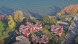 A residential area with red-roofed buildings, a body of water, and surrounding greenery. - Apartment with direct access to lake and close to dog park  (Sirmione)