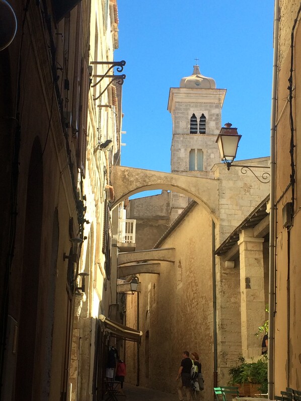 A narrow street with stone buildings, an arched bridge, and a tower with a cross on top. - Spacious, charming duplex with air conditioning and Wi-Fi in the heart of the citadel (Bonifacio)
