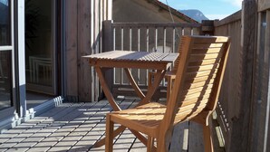 A wooden deck with a table and chair, a sliding glass door, and a wooden fence.