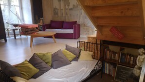 A cozy room with a bed, a purple sofa, and a bookshelf filled with books.