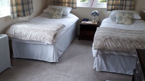 A bedroom with two beds, a nightstand, a desk, a chair, and a radiator. - Comfortable and spacious apartment in Middleton-by- Youlgrave near Bakewell.  (Middleton-by-Youlgrave)
