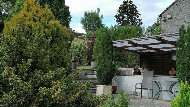A garden with potted plants, a pergola, and a stone wall. - Comfortable and spacious apartment in Middleton-by- Youlgrave near Bakewell.  (Middleton-by-Youlgrave)