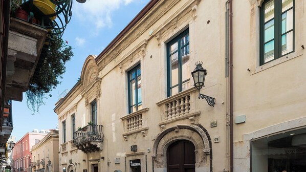 A street view with buildings featuring classical architecture, including ornate balconies and detailed facades.