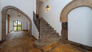 A staircase with stone steps and a metal railing, flanked by white walls and stone arches. - Varò Apartment (Taormina)
