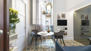 A modern living room with a round table, two chairs, a TV, and decorative items on shelves. - Varò Apartment (Taormina)