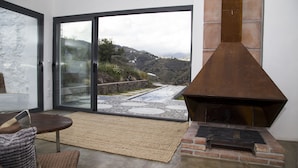 A modern living room with a fireplace, a glass door leading to a patio, and a view of a mountainous landscape. - El Morusco, huge views, perfect mountain walks, beaches & exploring Andalusia (torrox)