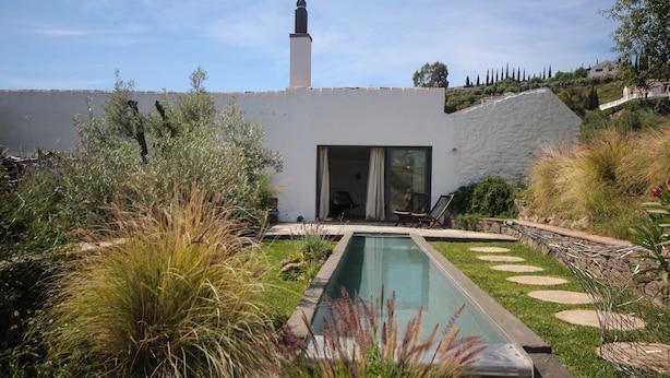 A modern pool area with a clear pool, surrounded by lush greenery and a white building with a chimney. - El Morusco, huge views, perfect mountain walks, beaches & exploring Andalusia (torrox)