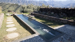 A rectangular pool with a stone border and stepping stones leading to it, surrounded by a stone wall and grass. - El Morusco, huge views, perfect mountain walks, beaches & exploring Andalusia (torrox)