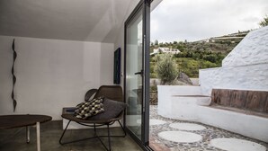 A modern room with a glass door leading to a patio. The room has a simple layout with a chair and a small table. The patio features a stone floor and a white wall. - El Morusco, huge views, perfect mountain walks, beaches & exploring Andalusia (torrox)