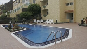 En swimmingpool med liggestole og en stenvæg.