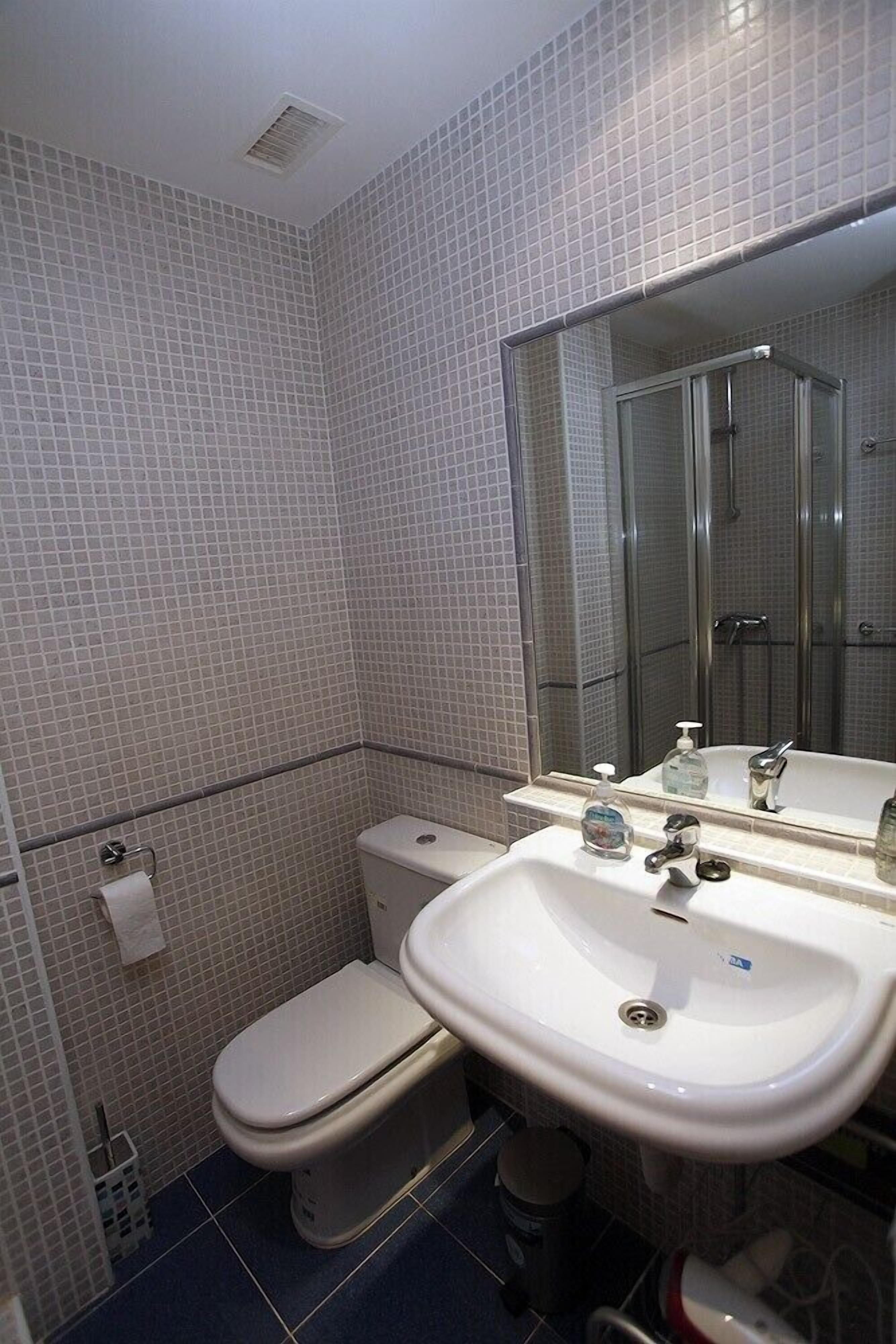 A bathroom with a toilet, sink, and shower.