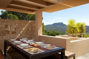 Mesa de comedor al aire libre con pared de piedra y vistas a montañas.