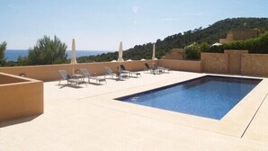 Una piscina en la azotea con sillones de descanso y vistas al mar.