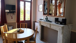 A dining area with a round table, wooden chairs, a fireplace, and framed artwork on the wall.