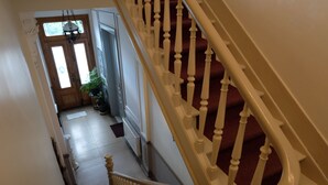 A staircase with white balusters and red carpeted steps leading to a door with a window.