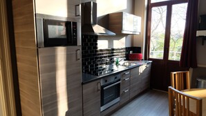 A modern kitchen with stainless steel appliances, wooden cabinets, and a large window providing natural light.