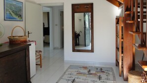 A hallway with a wooden staircase, a mirror, a patterned rug, and a wicker basket on a cabinet. - Villa, private pool,mountain views. Aircon included in price. Visit cinqueterre! (Vigneta)