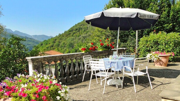 An outdoor patio with a table and chairs, a large umbrella, and potted plants. - Villa, private pool,mountain views. Aircon included in price. Visit cinqueterre! (Vigneta)