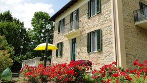 A stone building with green shutters, a balcony, and red flowers in the foreground. - Villa, private pool,mountain views. Aircon included in price. Visit cinqueterre! (Vigneta)