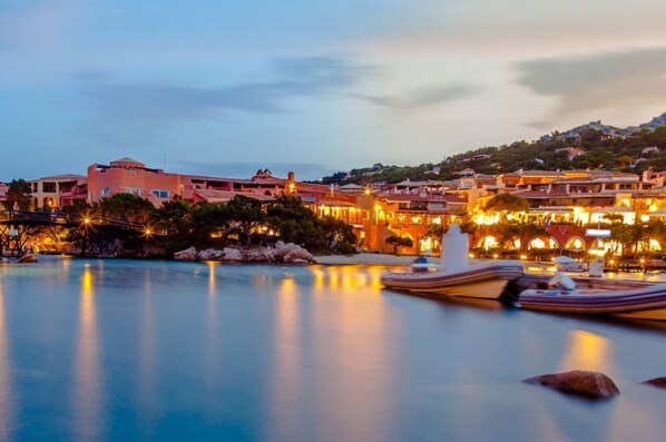 A coastal resort with multiple buildings, a swimming pool, and boats.