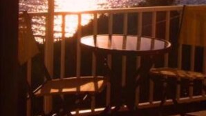 A balcony with a view of the sunset over the ocean, wooden chairs, and a round table. - Apartment/ flat - Sartène (Sartène)