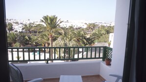 A balcony with a view of a coastal town, featuring palm trees and white buildings. - Thomas Beach House Costa Teguise (Costa Teguise)