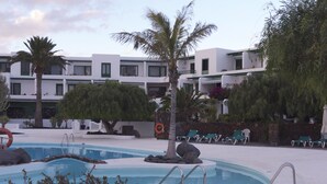 A pool area with lounge chairs, a lifebuoy, and a palm tree. - Thomas Beach House Costa Teguise (Costa Teguise)