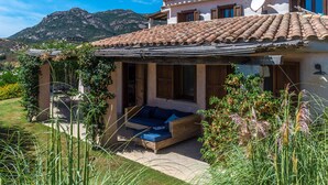 A Mediterranean-style villa with a tiled roof, a covered patio, and a mountain backdrop.