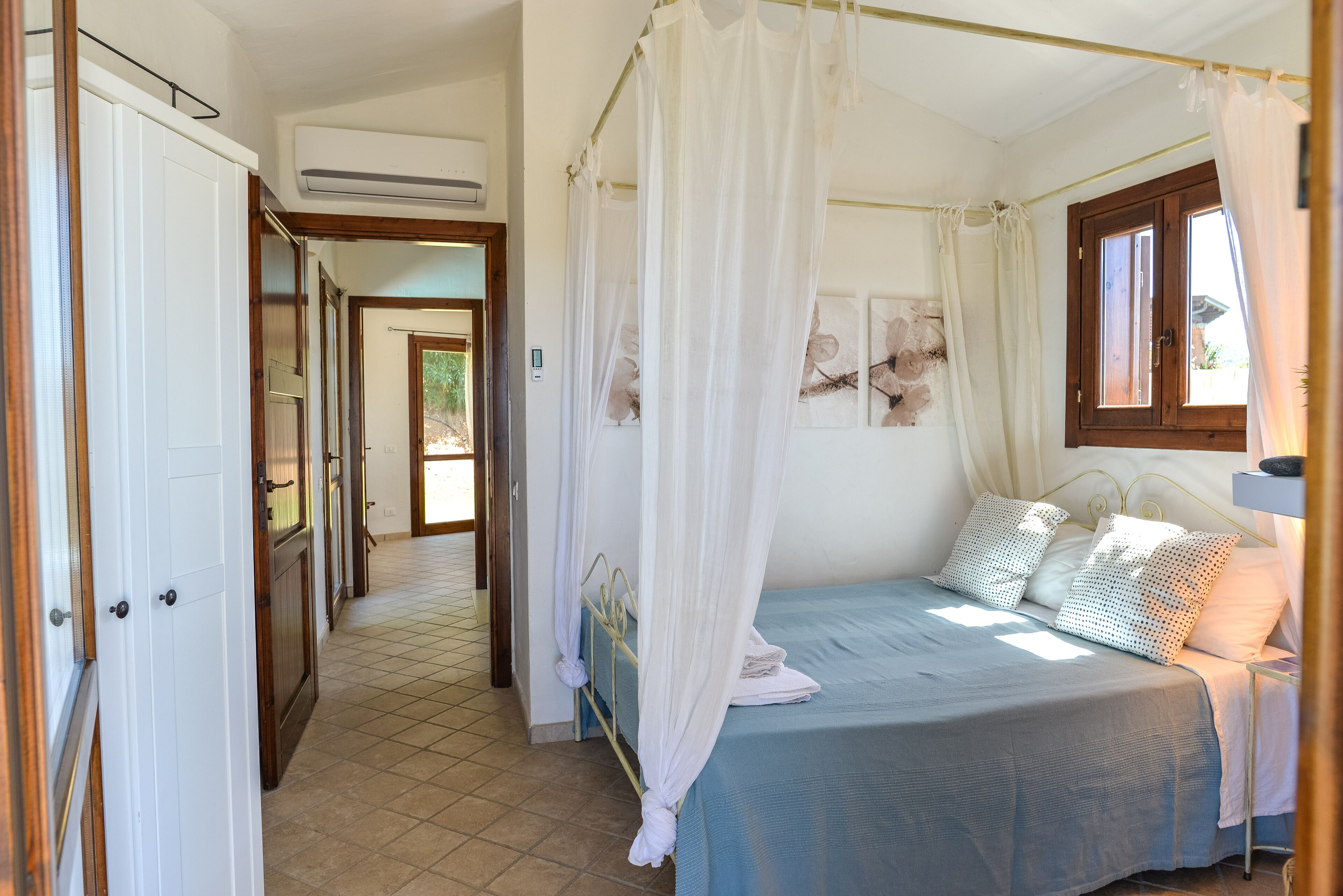 Une chambre à coucher avec un lit, un baldaquin, une fenêtre et une porte.