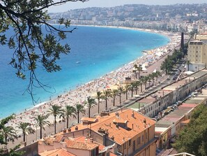 A coastal cityscape with a beach, palm trees, and buildings along the shore. - Air-conditioned villa, sea view and only 500m walk to sandy beach and San Peire! (Roquebrune-sur-Argens)