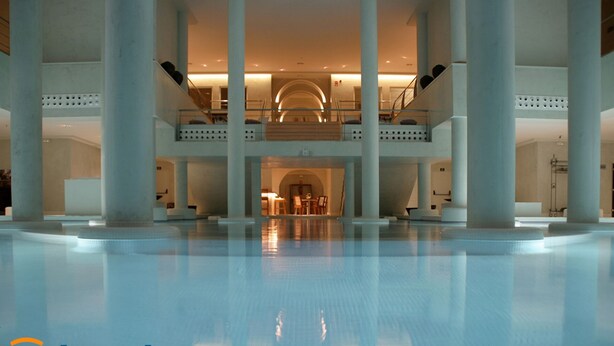 A spacious indoor pool area with a central seating area and multiple levels of balconies.