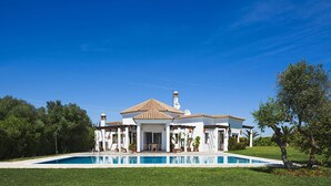 A two-story house with a swimming pool in front.