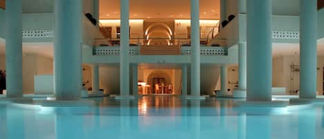 A spacious indoor pool area with a central seating area and multiple levels of balconies.