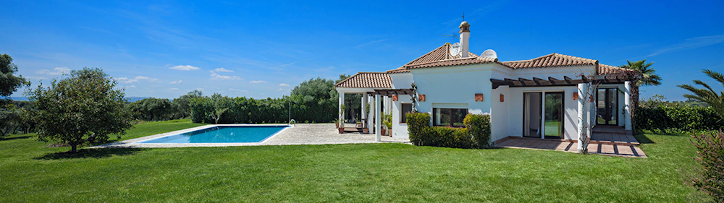 A two-story house with a swimming pool, a covered patio, and a garden.