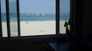 A room with a large window overlooking a beach with people and boats. - LE BIGORNEAU IMPRENABLE VIEW of the MORGAT CROZON BEACH (Crozon)